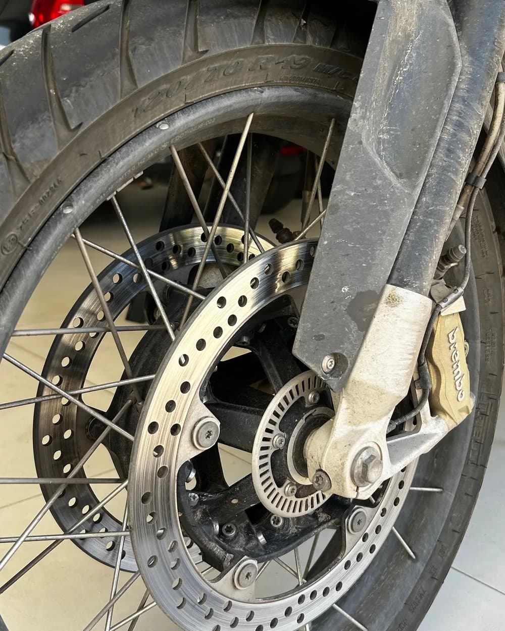 Roda de moto com sujeira acumulada no disco e na pinça