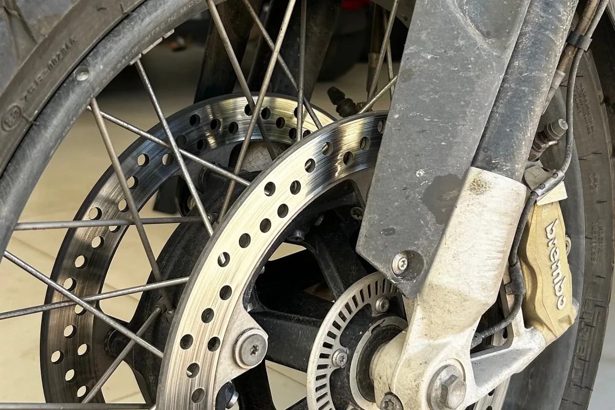 Roda de moto com sujeira acumulada no disco e na pinça